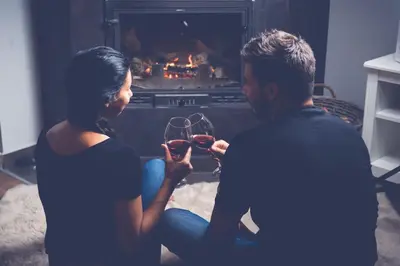a man and woman holding wine glasses in front of a fireplace at Prenociste Dunav 97 K3 in Novi Banovci