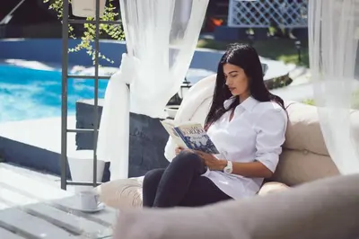 a woman sitting on a couch reading a book at Prenociste Dunav 97 K5 in Novi Banovci
