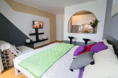 a bedroom with a large bed with purple and green pillows at Maxim in Belgrade