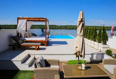 a patio with a bed and an umbrella and a pool at Harmonija na Dunavu in Smederevo