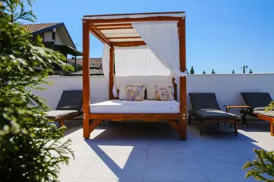a porch with a bed and two chairs on a patio at Harmonija na Dunavu in Smederevo