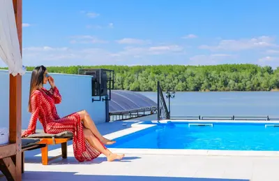 a woman in a red dress sitting on a bench next to a pool at Harmonija na Dunavu in Smederevo