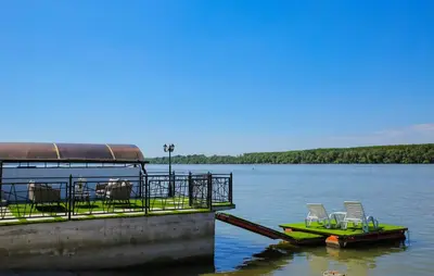a dock with chairs and a boat on the water at Harmonija na Dunavu in Smederevo