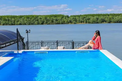 a woman in a red dress sitting next to a swimming pool at Harmonija na Dunavu in Smederevo