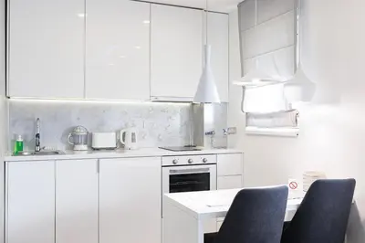 a kitchen with white cabinets and a table and chairs at White Apartments in Belgrade