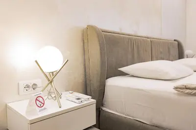 a bed with a lamp on a night stand next to a bed at White Apartments in Belgrade