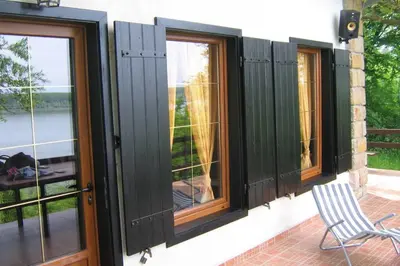 a room with three windows and a chair on a patio at Villa Kornelija in Stari Slankamen