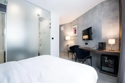 a bedroom with a bed and a desk and a tv at The Location Hotel in Belgrade
