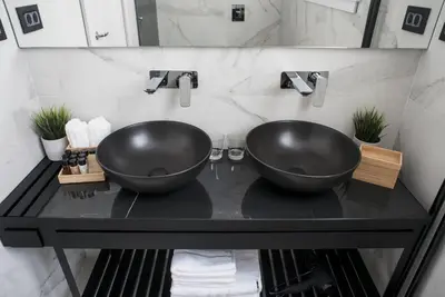 a bathroom with two black sinks on a black counter at The Location Hotel in Belgrade