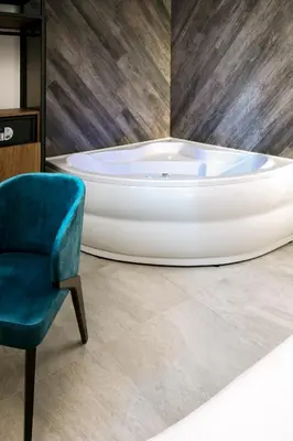 a bath tub and a chair in a room at The Location Hotel in Belgrade