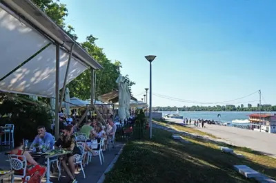a group of people sitting at tables near the beach at Villa Tower Gardos in Belgrade