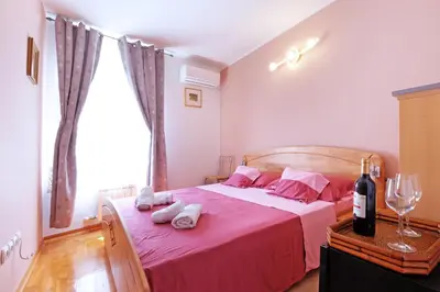a bedroom with a bed with pink sheets and a window at Villa Tower Gardos in Belgrade