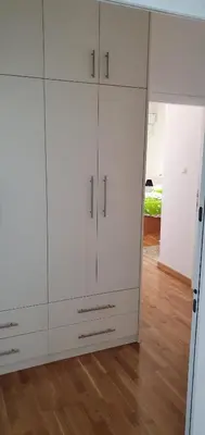 a white cabinet in a room with a wooden floor at Julija in Pančevo