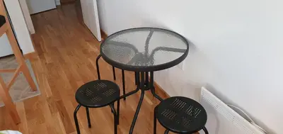 a glass table and two stools in a room at Julija in Pančevo