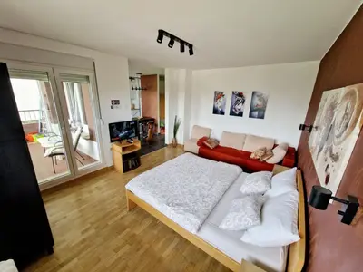 a bedroom with a large bed and a red couch at Apartment Nena in Tošin Bunar