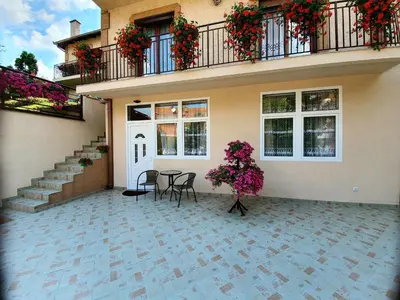 a house with a patio with a table and flowers at Nilena apartmani in Smederevo