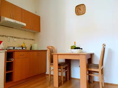 a kitchen with a table and chairs and a clock on the wall at Nilena apartmani in Smederevo