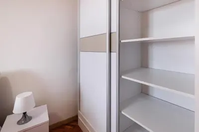 a closet with white shelves and a lamp on a table at Apartment Paradise Fantasy in Belgrade