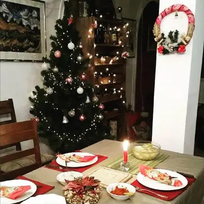 a christmas tree in a room with a table with a candle at Kuća na dan Villa Holiday in Sakule