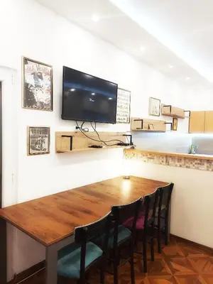 a dining room table with chairs and a television on a wall at MAGENTA Apartments in Belgrade