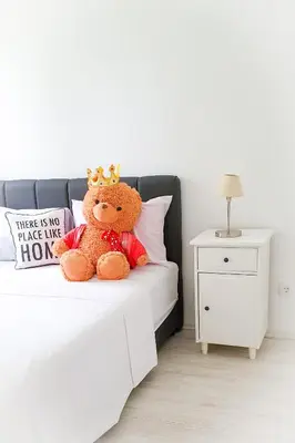 a teddy bear wearing a crown sitting on a bed at Apartment Iskra in Belgrade