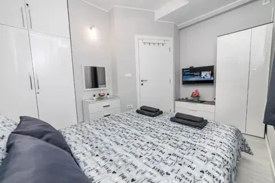 a white bedroom with a bed and a tv at Gray Luxe in Belgrade