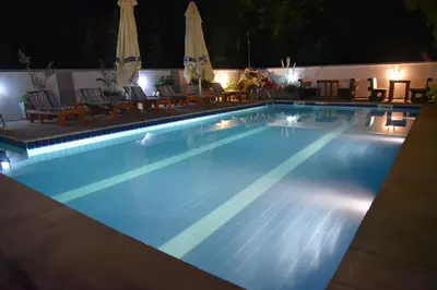 a swimming pool at night with chairs and umbrellas at Villa Boho Cherga in Belgrade