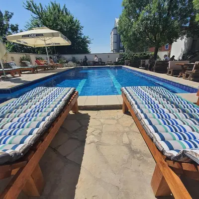 a swimming pool with two chairs and an umbrella at Villa Boho Cherga in Belgrade