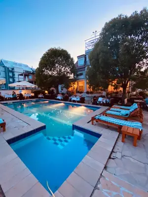 a swimming pool with two loungers in front of a hotel at Villa Boho Cherga in Belgrade