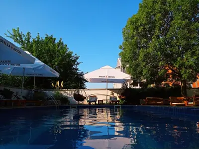 a swimming pool with an umbrella and a table and chairs at Villa Boho Cherga in Belgrade