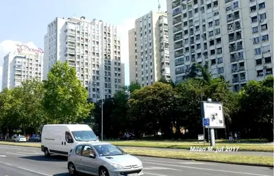 a silver car driving down a street with tall buildings at High White Apartments in Belgrade