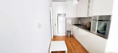 a kitchen with white cabinets and a wooden floor at High White Apartments in Belgrade