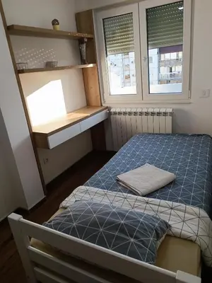 a small room with a bed and two windows at Serbian home, Gandijeva 162, free parking in Belgrade