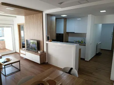 a room with a kitchen and a living room with a table at Serbian home, Gandijeva 162, free parking in Belgrade