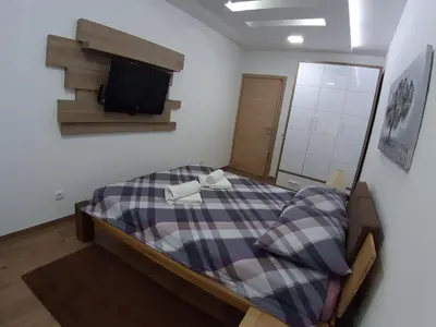 a bedroom with a bed with a tv on the wall at Serbian home, Gandijeva 162, free parking in Belgrade