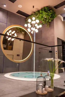 a bathroom with a hot tub with a round mirror at Marconio Wellness Private Pool & SPA - City Center in Belgrade