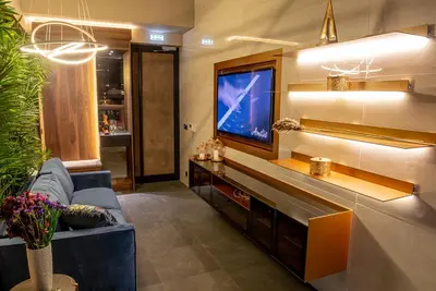 a living room with a tv and a blue couch at Marconio Wellness Private Pool & SPA - City Center in Belgrade