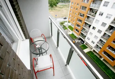 a balcony with a red chair and a table at Apartment Moonstone 1 in Belgrade