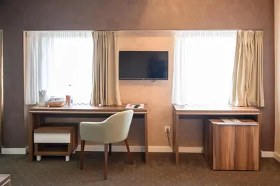 a hotel room with a desk and two windows at MV Monogram in Inđija