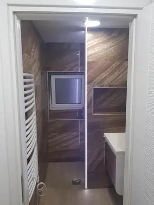 a bathroom with a tv in a room with wooden walls at studio skadarlija in Belgrade