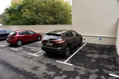 two cars parked in a parking lot in front of a building at Hotel LoRa in Belgrade