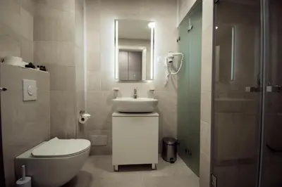 a bathroom with a sink and a toilet and a mirror at Hotel LoRa in Belgrade