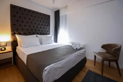 a bedroom with a large bed and a chair at Hotel LoRa in Belgrade