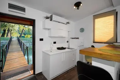 a kitchen with white cabinets and a table and a balcony at Beach House Belgrade in Belgrade