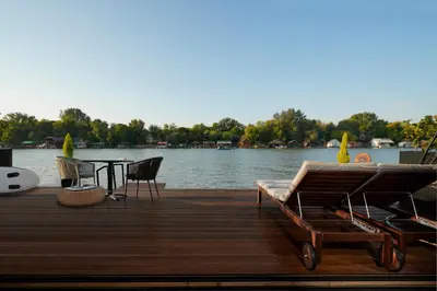 a dock with chairs and a table on the water at Beach House Belgrade in Belgrade