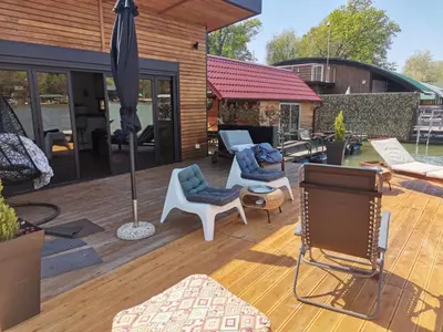 a patio with chairs and an umbrella on a wooden deck at Beach House Belgrade in Belgrade