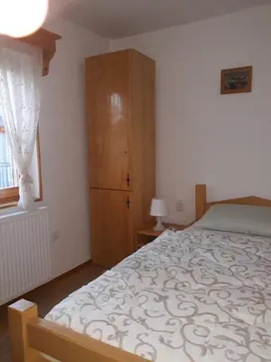 a bedroom with a bed and a wooden cabinet at Rita Apartman & Studio in Zrenjanin