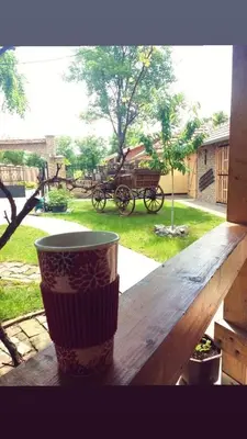 a coffee cup on a wooden table with a horse drawn carriage at Rita Apartman & Studio in Zrenjanin