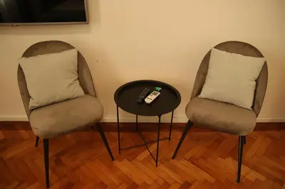 two chairs and a table with a remote control at Natalie's Royal M in Belgrade