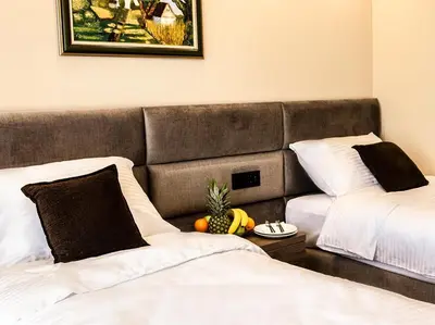 a hotel room with two beds and a fruit on a table at Garni hotel FILIA in Nova Pazova